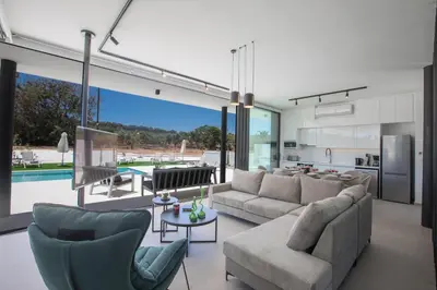 a living room with a couch and chairs and a kitchen at Elite Pearl Villas in Protaras