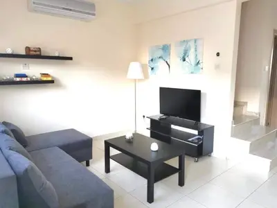 a living room with a blue couch and a tv at Protaras Ionian Breeze House in Paralimni