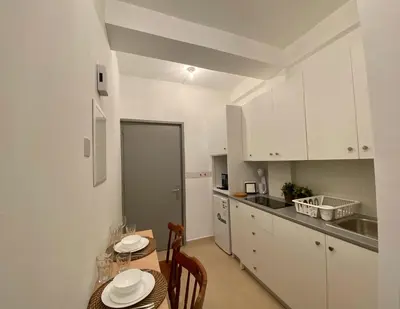a kitchen with white cabinets and a table and chairs at Central Suites Down Town Nicosia in Nicosia