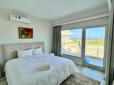 a bedroom with a large bed and a large window at Emerald Suites in Protaras