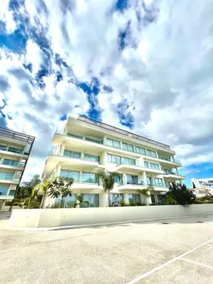 a large white building with palm trees in front of it at Emerald Suites in Protaras