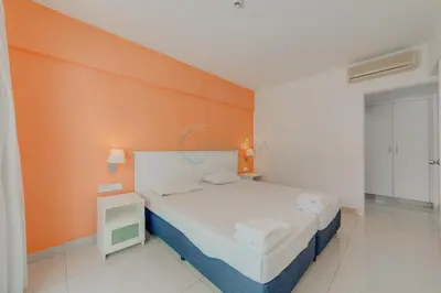 a bedroom with a bed with an orange wall at Christos Napa Self Serviced Apartments in Ayia Napa