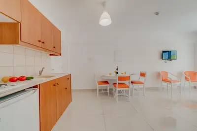 a kitchen with orange chairs and a table in it at Christos Napa Self Serviced Apartments in Ayia Napa