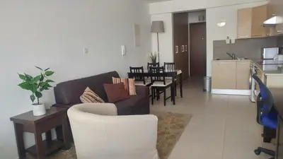 a living room and kitchen with a couch and a table at Pyla Gardens A202 Studio in Pyla