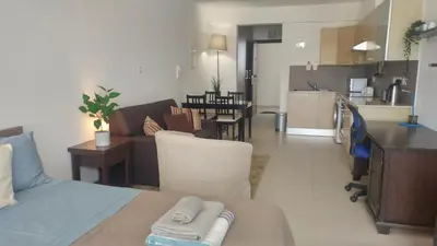 a living room and kitchen with a couch and a table at Pyla Gardens A202 Studio in Pyla