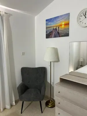 a bedroom with a chair and a bed and a clock at Mersey Faros Complex in Pervolia