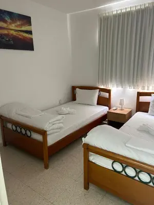 two twin beds in a room with a window at Mersey Faros Complex in Pervolia