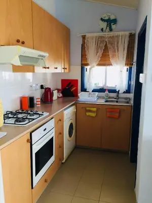 a kitchen with wooden cabinets and a stove top oven at Artist Cottage in Dromolaxia in Larnaka