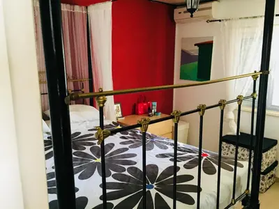 a bedroom with a bed and a red wall at Artist Cottage in Dromolaxia in Larnaka