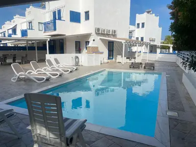 a swimming pool with chairs and a house at Olive Tree Villa - Protaras in Protaras