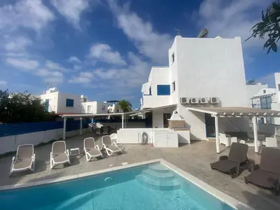 a villa with a swimming pool in front of a building at Olive Tree Villa - Protaras in Protaras