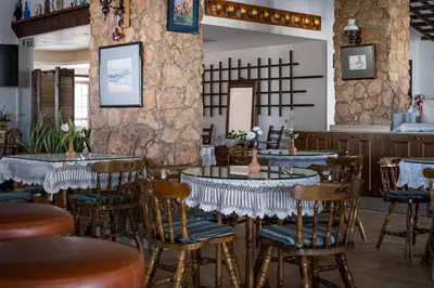 a restaurant with tables and chairs and a stone wall at Anais Bay Hotel in Protaras