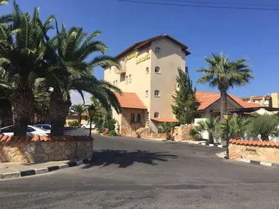a large white building with palm trees and a street at Anais Bay Hotel in Protaras