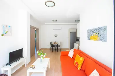 a living room with a orange couch and a tv at Panayia Sea View Apts in Protaras