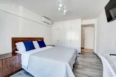 a bedroom with a bed with blue pillows and a tv at MyHome DeLux, Ayia Napa 3 Bedroom with Pool in Ayia Napa