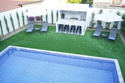 a backyard with a swimming pool and a bar with umbrellas at Kamaroporta Luxury Apartments in Ayios Theodhoros