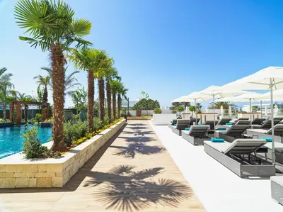 an image of a resort pool with lounge chairs and palm trees at Amanti, MadeForTwo Hotels - Ayia Napa in Ayia Napa