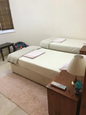 two beds in a room with a table and a lamp at VillaHoliday in Voroklini