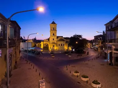a building with a clock tower on a street at VillaHoliday in Voroklini