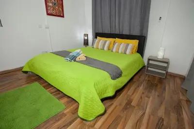 a green bed in a room with a wooden floor at Nefeli Sea Side, Boutique Apartment in Limassol