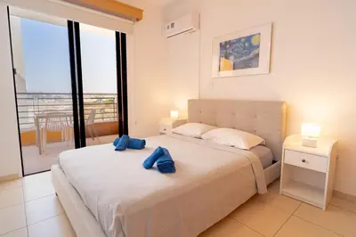 a bedroom with a bed with two blue towels on it at Mirabella Mackenzie 1 Bedroom Flat Near the Sea in Larnaka