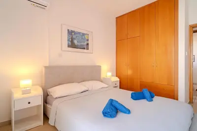 a bedroom with a bed with blue towels on it at Mirabella Mackenzie 1 Bedroom Flat Near the Sea in Larnaka