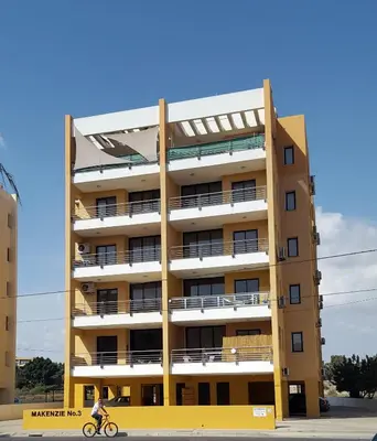 a person riding a bike in front of a building at Mirabella Mackenzie 1 Bedroom Flat Near the Sea in Larnaka