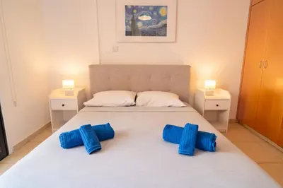 a bedroom with a large bed with blue pillows on it at Mirabella Mackenzie 1 Bedroom Flat Near the Sea in Larnaka