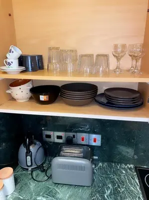 a shelf with plates and glasses and a printer at Larnaca Room, 50m to the Finikoudes beach in Larnaka