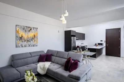 a living room with a gray couch and a kitchen at Solaar Apartments st Lazarous in Larnaka