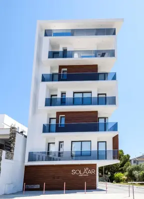 a tall white building with a sign on it at Solaar Apartments st Lazarous in Larnaka