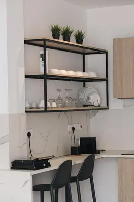 a kitchen with a table with chairs and shelves at Caramela Luxury Apts in Ayia Napa