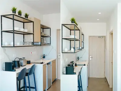 a kitchen with a counter with chairs and shelves at Caramela Luxury Apts in Ayia Napa