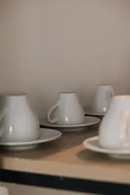 three white tea cups and saucers on a table at Caramela Luxury Apts in Ayia Napa