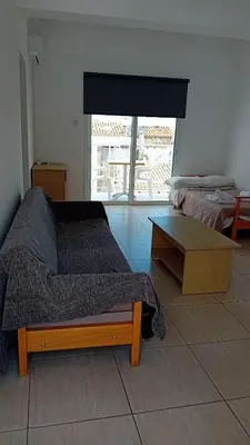 a bedroom with a bed and a table and a window at Napa Charles Apts in Ayia Napa