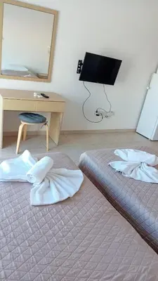 a bedroom with two beds and a desk and a mirror at Napa Charles Apts in Ayia Napa