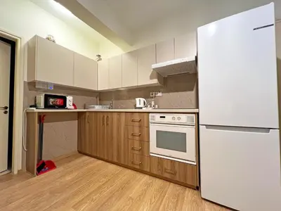 a kitchen with a white refrigerator and wooden cabinets at Albert's Apartment Mackenzie 001 in Larnaka