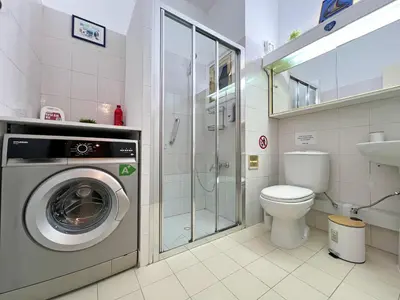 a bathroom with a washing machine and a toilet at Albert's Apartment Mackenzie 001 in Larnaka