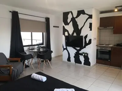 a living room with a tv and a kitchen at St Lazaros, Larnaca Center Studio in Scala