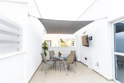 a patio with a table and chairs on a white wall at Spiros Luxury Apartments in Ayia Napa