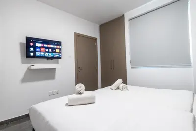 two beds in a room with a tv on the wall at Spiros Luxury Apartments in Ayia Napa