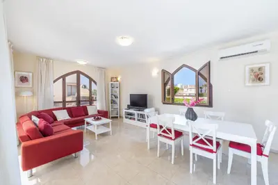 a living room with a red couch and a table at Protaras Villa Elena 3 in Protaras