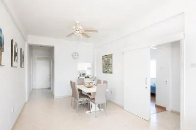 a white dining room with a table and chairs at Apollon Sea View Beachfront Ap 302 in Larnaka