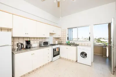 a kitchen with white cabinets and a washer and dryer at Apollon Sea View Beachfront Ap 302 in Larnaka