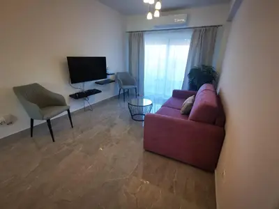 a living room with a red couch and a television at Hawaii Holiday Apartment 41 in Limassol