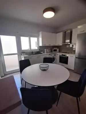 a kitchen with a white table and chairs in it at Hawaii Holiday Apartment 41 in Limassol