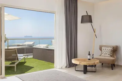 a living room with a table and a view of the ocean at Atlantica Bay - Adults Only in Limassol