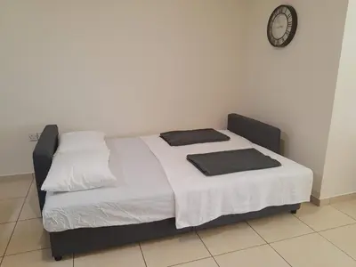 a bed in a room with a clock on the wall at Larnaca Xylophagou 2-bedroom apartment with a shaded terrace in Xylophaghou