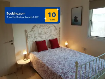 a bedroom with a bed with red pillows and a window at Larnaca Xylophagou 2-bedroom apartment with a shaded terrace in Xylophaghou