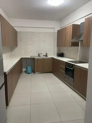 a kitchen with wooden cabinets and a white tile floor at Central Large 2BD APT near the Beach in Larnaka